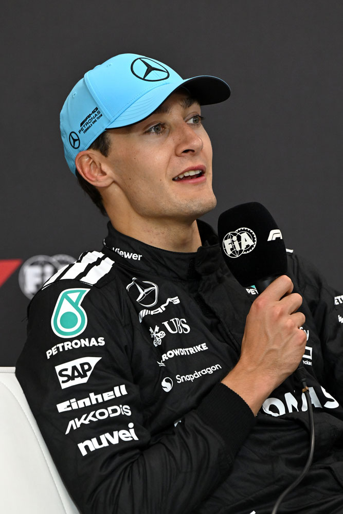 Formel 1-føreren George Russell med en mikrofon i høyre hånd.