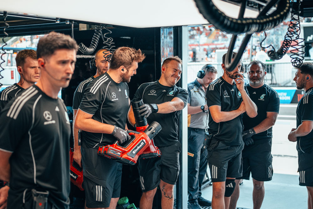 Mercedes-AMG PETRONAS Formula One Team er i garasjen. To teammedlemmer holder røde trådløse blåsemaskiner fra Einhell og gjør seg klare til neste handling.