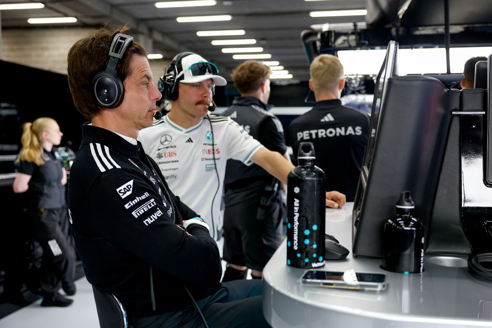 Toto Wolff og Valtteri Bottas fra Mercedes-AMG PETRONAS Formula One Team sees ved teamets arbeidsstasjon i garasjen. De er fokusert på løpsstrategien, ser på monitorene og kommuniserer via hodetelefoner.
