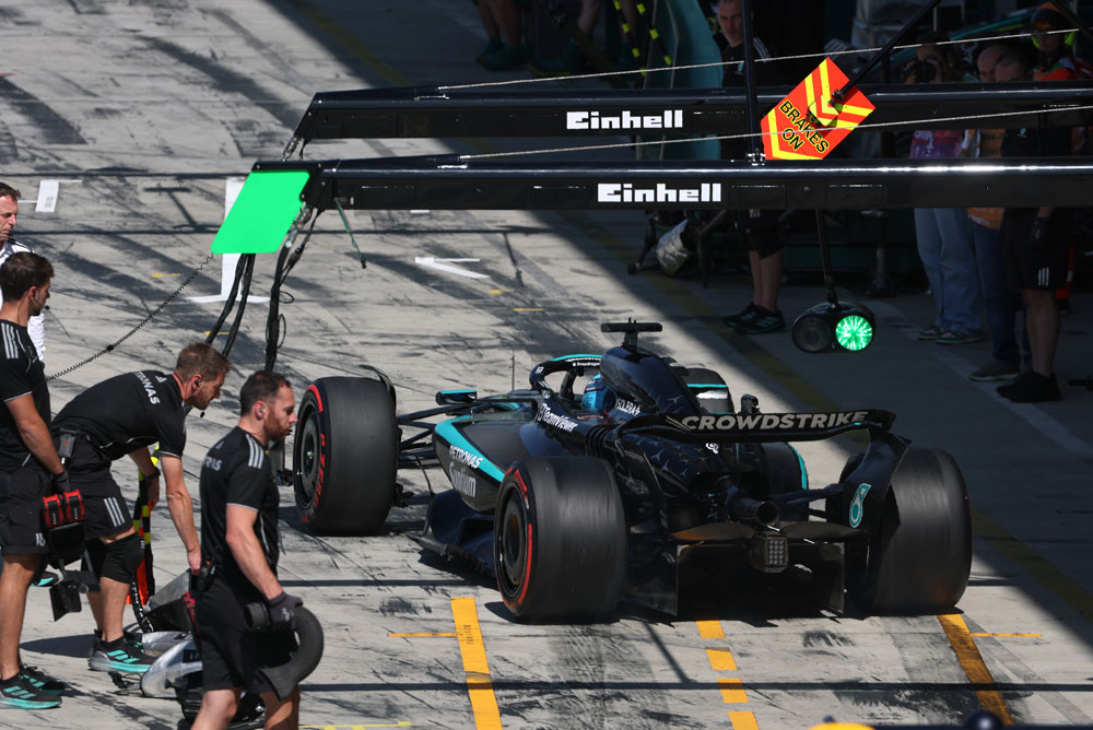 En Mercedes-AMG PETRONAS Formula One-bil står i pit lane under et pitstopp. Flere teammedlemmer er samlet rundt bilen. Einhell-logoen er synlig over pit-området.