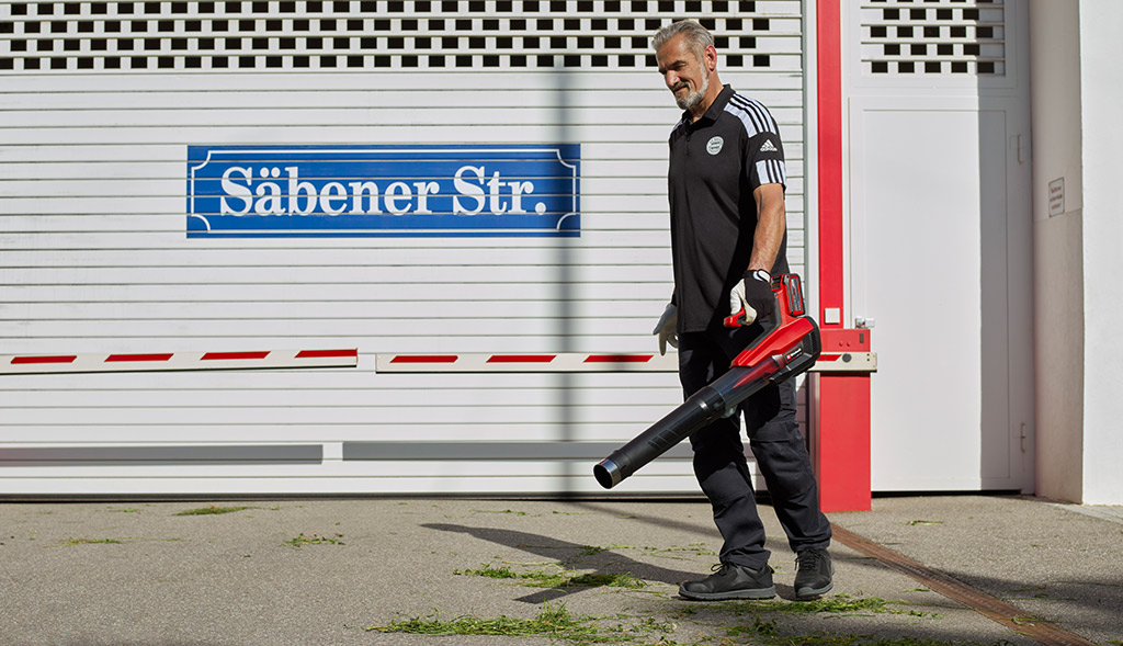 A man blows away the grass with a leaf blower