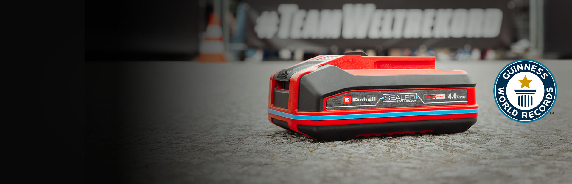 Einhell SEALED-batteri Power X-Change 4,0 Ah ligger på asfalten, med logoen “Record Holder” for Guinness World Records til høyre.