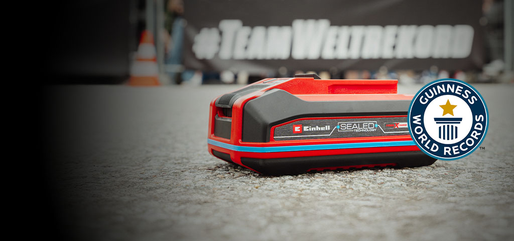 Einhell SEALED-batteri Power X-Change 4,0 Ah ligger på asfalten, med logoen “Record Holder” for Guinness World Records til høyre.